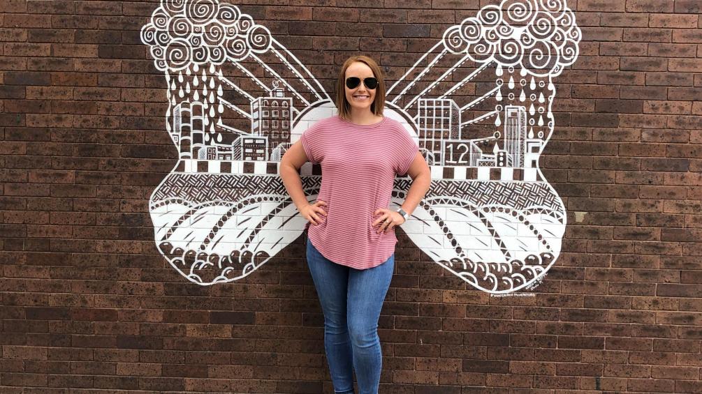 woman standing in front of flood wings mural at flood control stroll